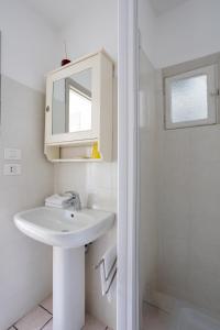 a white bathroom with a sink and a shower at Il Cortile di Mamma Mia in Pisano