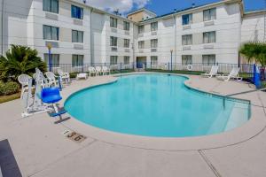 a pool in front of a hotel with chairs and a building at Motel 6-Katy, TX - Houston in Katy