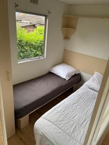 a small bedroom with a bed and a window at Mobilhomme in Brêmes