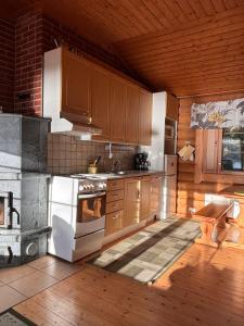 a kitchen with wooden cabinets and a stove at Kalliorinteen Mökit Lehtipirtti in Töysä