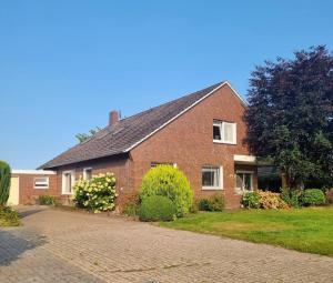 a brick house with a driveway in front of it at Robbenglück Tossens - Ruhe, Garten und Nordseegefühl in Tossens
