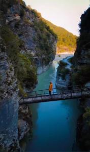 a person walking across a bridge over a river at Canyon River House in Çorovodë