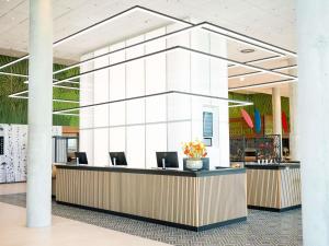 a lobby with a reception desk with chairs at IBIS STYLES MUENCHEN AIRPORT in Munich