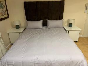 a large white bed with two nightstands and two lamps at Adorable Pool Side Apartment in Monte Vista