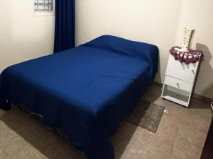 a bed with a blue blanket and a dresser in a room at Depto Clarita in Belén