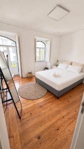 a bedroom with a large white bed and wooden floors at Avenidas Prime Lisbon in Lisbon