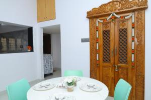 a dining room with a table and a wooden door at Sarva Tranquil home stay in Kumbakonam