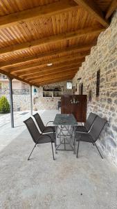 a patio with a table and chairs and a stone wall at Αρχοντικό Κάτω Βρύση in Levidi