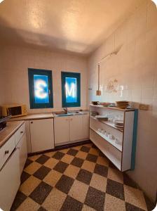 a kitchen with white cabinets and a checkered floor at Résidence 3 M in Jāmi‘ al Guelloufi +13 photos