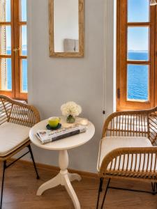 a table with a bowl of flowers and two chairs at Arion Syros Luxury Rooms and Suites in Ermoupoli