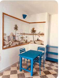 a blue table and chairs in a room with a painting at Résidence 3 M in Jāmi‘ al Guelloufi