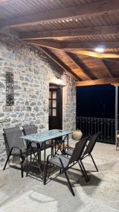 a table and chairs in front of a stone wall at Αρχοντικό Κάτω Βρύση in Levidi
