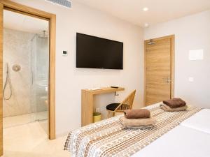 a bedroom with a bed with a television on the wall at Hotel Ses Puntetes in Cala d´Or