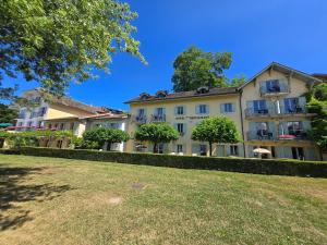 a large building with trees in front of a yard at Hôtel La Riviera Victoria in Yvoire