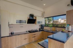 a kitchen with wooden cabinets and a large window at The Mountain house 4 BHK VIlla With Pool in Rishīkesh +38 photos