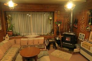 een woonkamer met een bank en een houtkachel bij Pension Agi in Hakuba