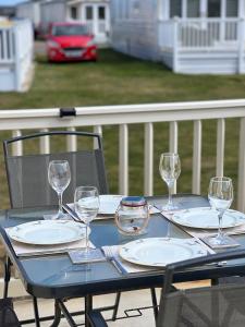 a table with plates and wine glasses on a porch at Aurora Beacon View in Lossiemouth