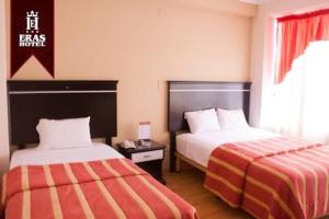 a hotel room with two beds and a window at Eras Hotel in Chiclayo
