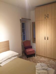 een slaapkamer met een bed, een stoel en een kast bij Rose Building Apartment in Cospicua