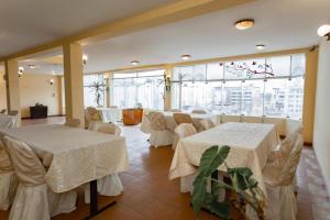 a room with white tables and chairs and large windows at Eras Hotel in Chiclayo
