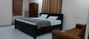 a bed in a room with a chair and a bed sidx sidx sidx at Hotel N Pride in Guntūr +8 photos