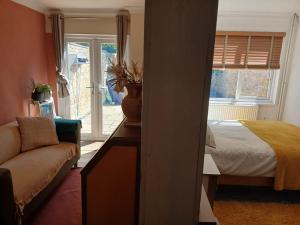 a bedroom with a bed and a couch and a window at Bottisham Cosy Double in Bottisham