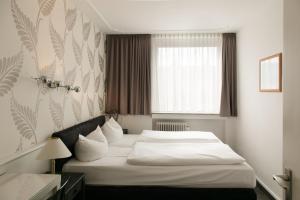 a hotel room with a bed and a window at Hotel Krone Aachen | City-Eurogress in Aachen