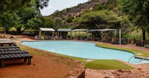 a swimming pool with tables and chairs in a park at Mabalingwe Nature Reserve - Elephant Lodge - Tjaila in Warmbaths