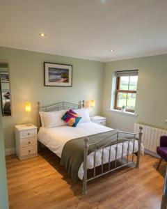 a bedroom with a bed and two windows at Radharc Sléibhe in Kilgarvan
