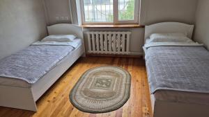 two beds in a room with a rug on the floor at Stay Osh in Osh