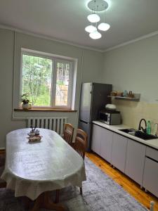 a kitchen with a table and a kitchen with a refrigerator at Stay Osh in Osh