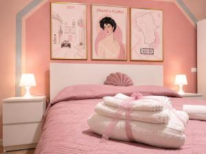 a bedroom with a pink bed with a pile of towels at Torre Florio in Campofelice di Roccella