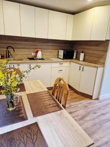 a kitchen with white cabinets and a table with flowers at Brīvdienu māja Vecdaugavā in Riga