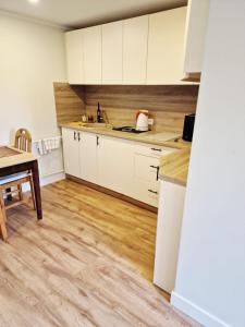 a kitchen with white cabinets and a wooden floor at Brīvdienu māja Vecdaugavā in Riga