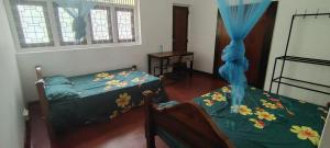 a bedroom with two beds and a table and a window at Deepthi Villa in Nikawatawana