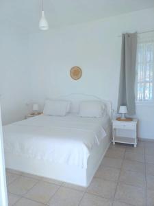 a white bed in a white bedroom with a window at Georgia Rooms Milos in Plaka Milou