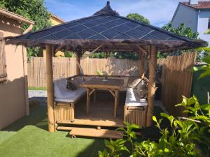 a wooden gazebo with a table and a bench at Le Frais Jus in Fréjus