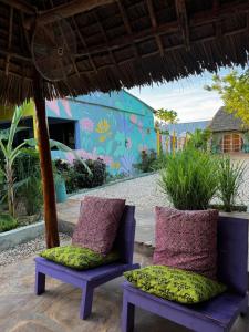 a pair of chairs sitting under an umbrella on a patio at FURAHA GARDEN Rooms in Kendwa