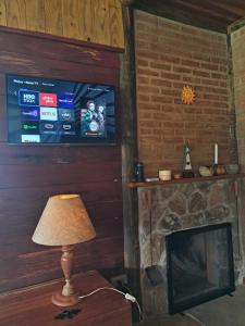 a room with a television and a lamp next to a fireplace at Cabana do Sol -São Francisco Xavier in São José dos Campos