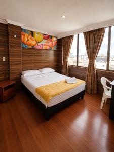 a bedroom with a bed with a painting on the wall at Hotel Ejecutivo 63 In in Bogotá