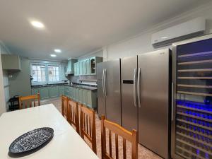 a kitchen with a table and a stainless steel refrigerator at Masia Botargo. 9 hab, 8 baños, piscina, porche in L'Aldea
