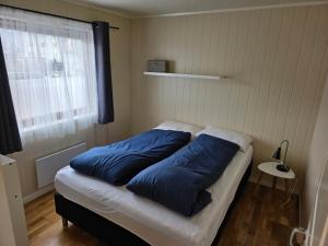 a bed in a room with blue pillows on it at T&T Vardø in Vardø