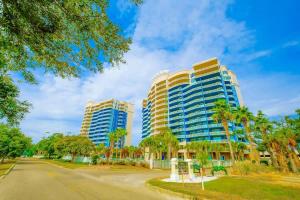 two tall buildings with palm trees in front of a street at Legacy Tower I in Gulfport