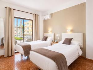 two beds in a hotel room with a window at Pensión Rocamar in Almuñécar +59 photos