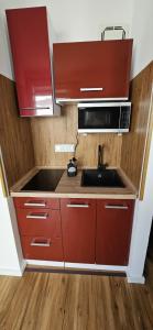 a kitchen with red cabinets and a sink and a microwave at Golden Leaf Apartment with Parking in Burghausen +36 photos