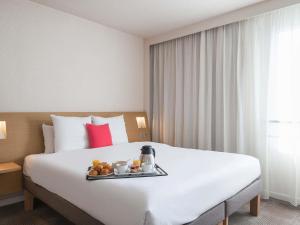 a hotel room with a bed with a tray of food on it at Novotel Paris Est Centre de Conférence in Bagnolet +166 photos