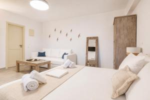 a white bedroom with a white bed and a couch at Marilia ViIlage Spathi Kea "Studio The Goat" in Spathi 