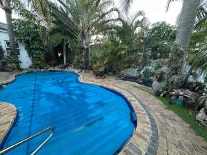 a large blue swimming pool in a yard with palm trees at Adorable Pool Side Apartment in Monte Vista