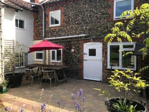 a patio with a table and a red umbrella at Spacious Suffolk Cottage in Village Setting in Westleton