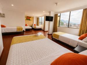 a hotel room with two beds and a large window at Hotel Ejecutivo 63 In in Bogotá